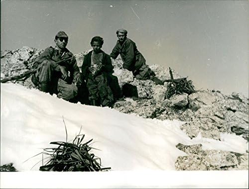 Vintage fotografija dva vojnika i dječaka koji sjede na snježnoj i stjenovitoj planini.